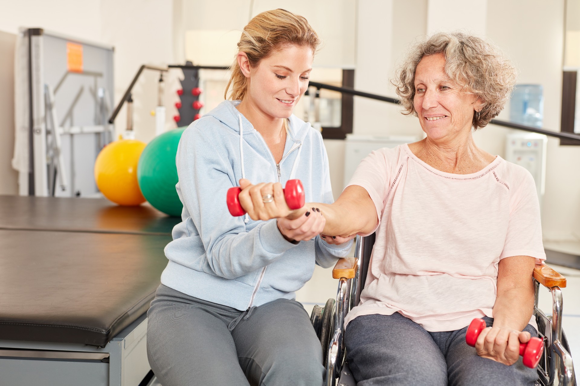 senior lady in a wheelchair in rehabilitation holding weights