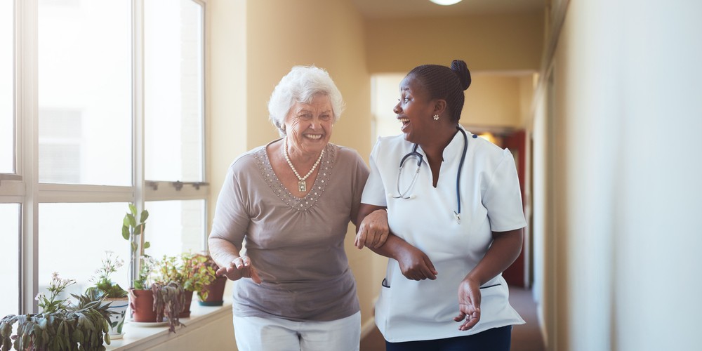 assisted living nurse walking with a happy senior woman