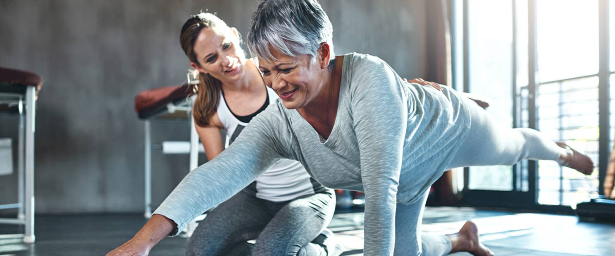 senior lady in rehabilitation stretching with the help of a healthcare worker