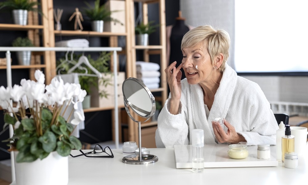 Happy senior woman applying facial cream