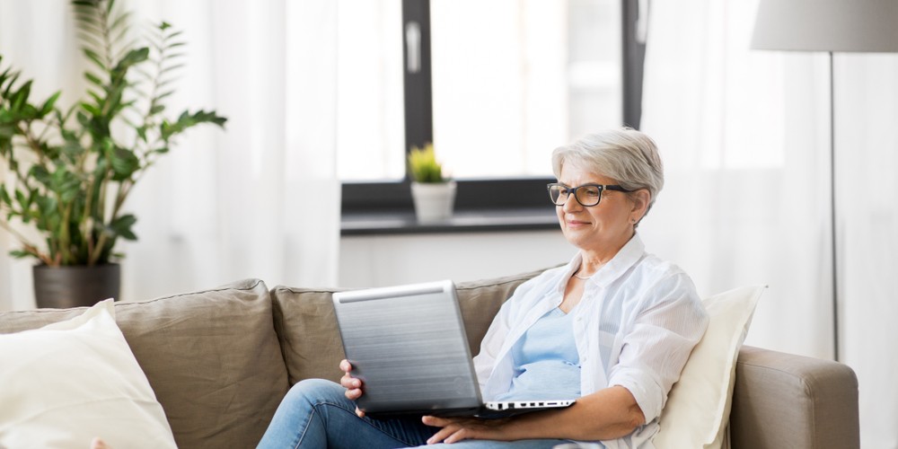 happy senior woman in glasses using laptop
