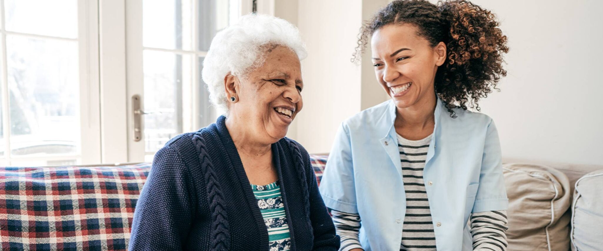 healthcare worker laughs with an elderly woman
