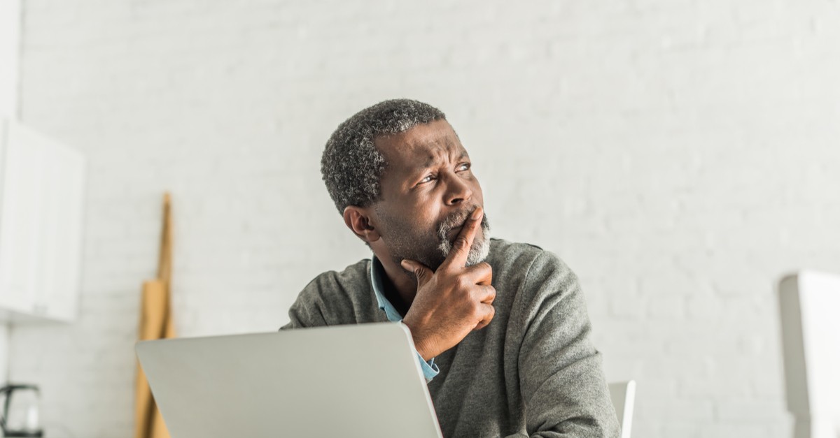 Thoughtful senior man looking away from his computer