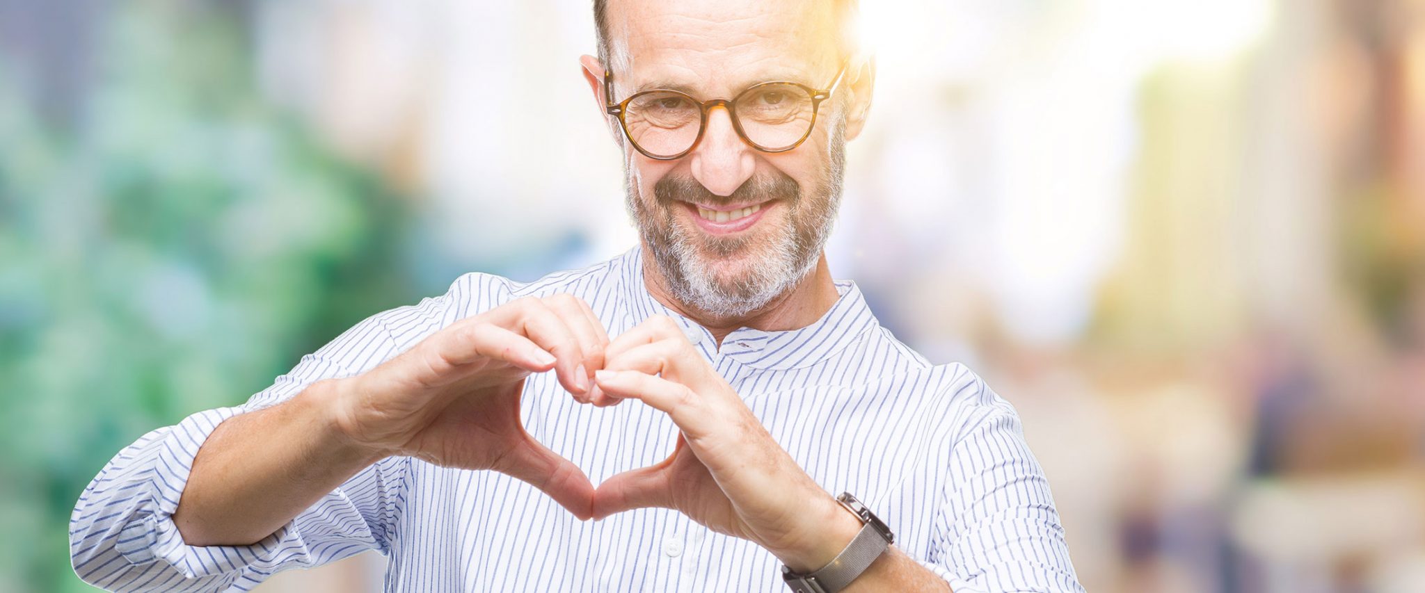 senior man holding up his hands in the shape of a heart