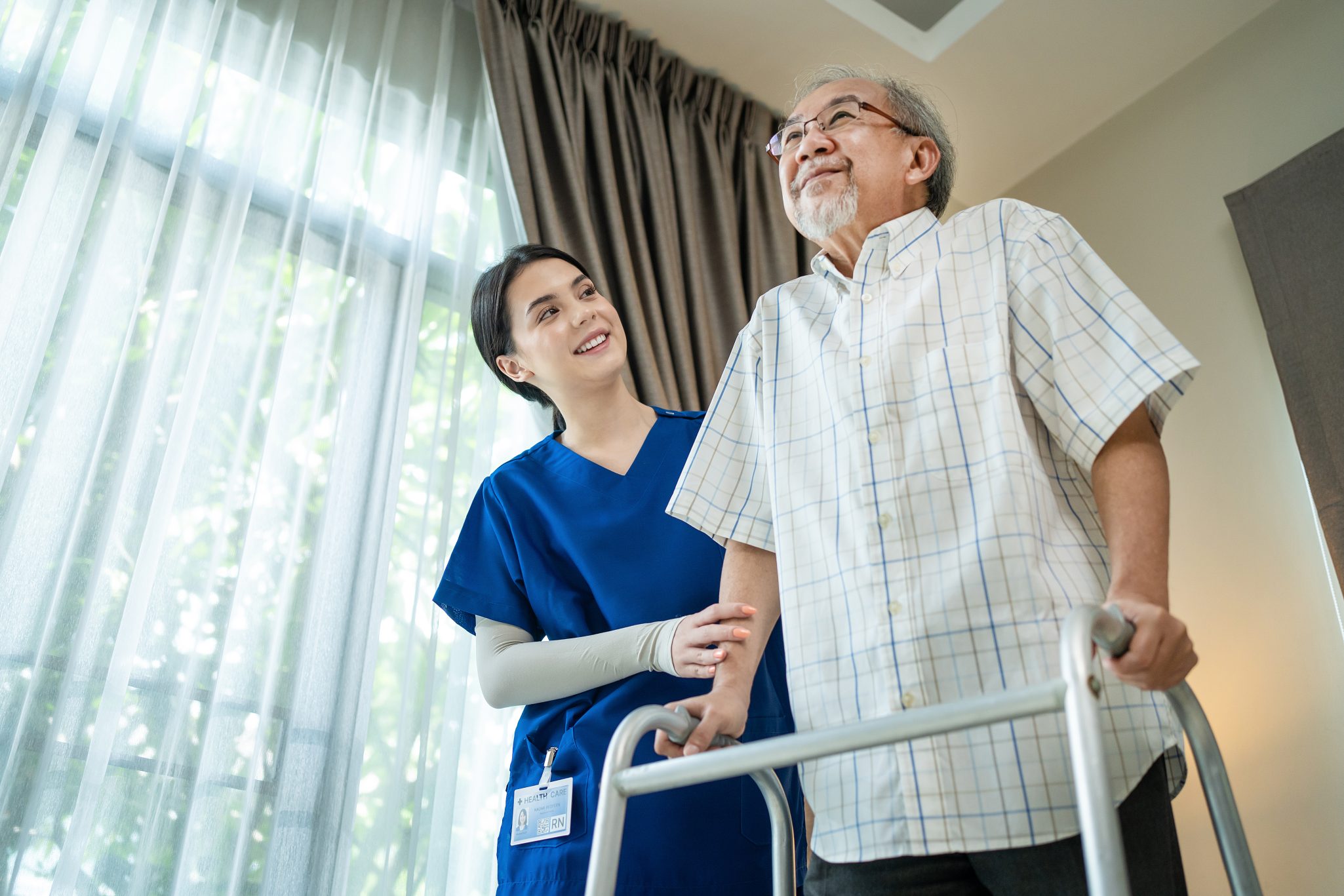Female nurse assisting senior man with walker