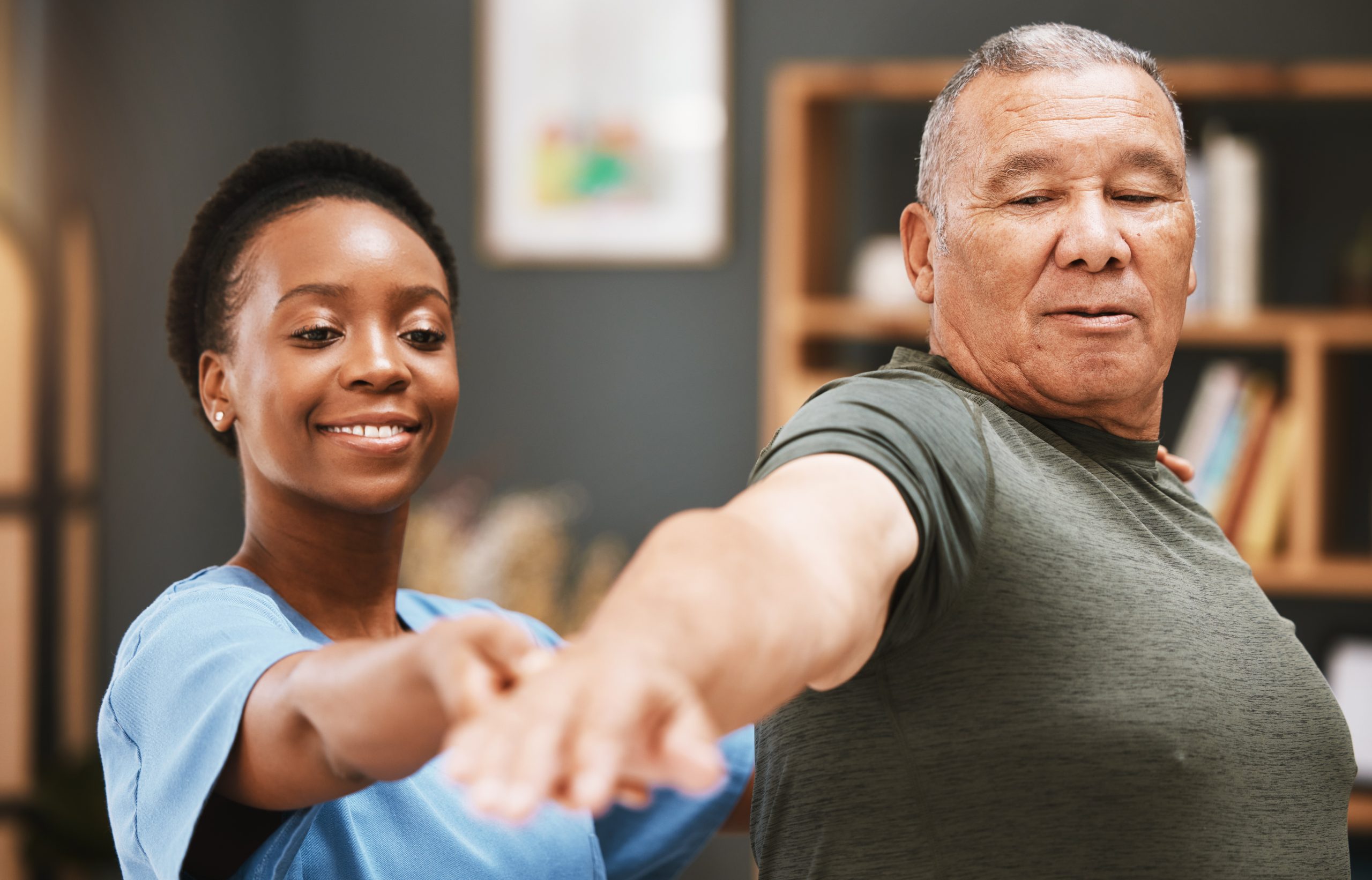 Physical therapist assisting senior man in arm exercises