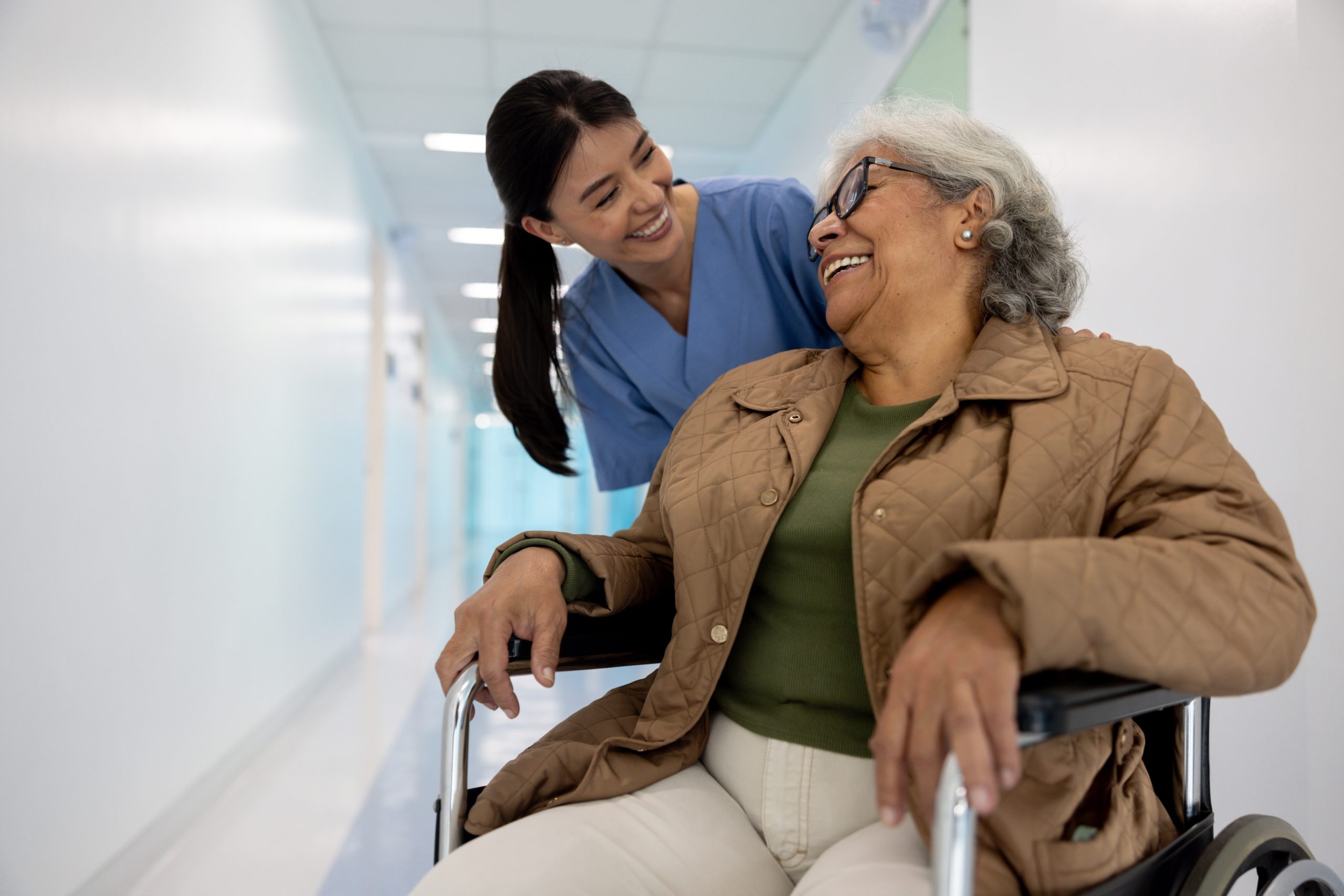 Female nurse smiling at senior woman in wheelchair