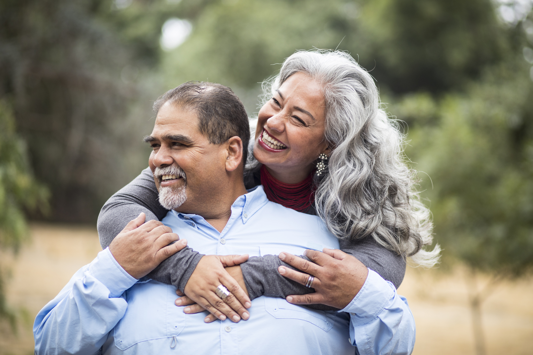 Senior couple smiling while hugging each other from behind